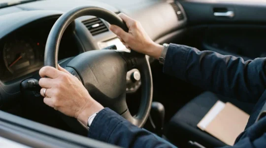 Conducteur satisfait au volant d'un véhicule économique avec documents d'assurance
